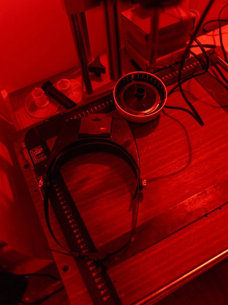 A Rohde & Schwarz CMW500 wideband radio tester on a lab bench with green status LEDs and a phone under test.